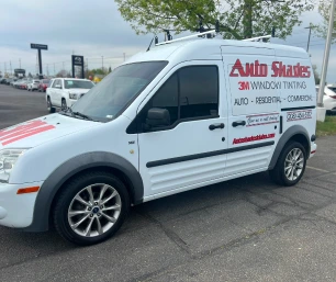 White service van with "Auto Shades 3M Window Tinting" branding on the side, advertising auto, residential, and commercial tinting services, parked in a lot near other vehicles.