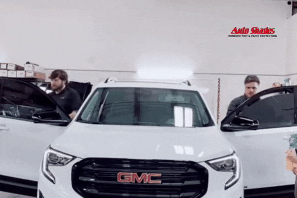 Two technicians from Auto Shades Idaho install window tint on a white GMC SUV inside a clean shop, showcasing professionalism and quality service—key elements of What Window Tinting Really Is in Caldwell and Nampa.