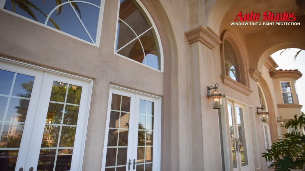 Exterior of a large upscale home with white French doors and arched windows, all featuring residential window tinting for UV protection and privacy.