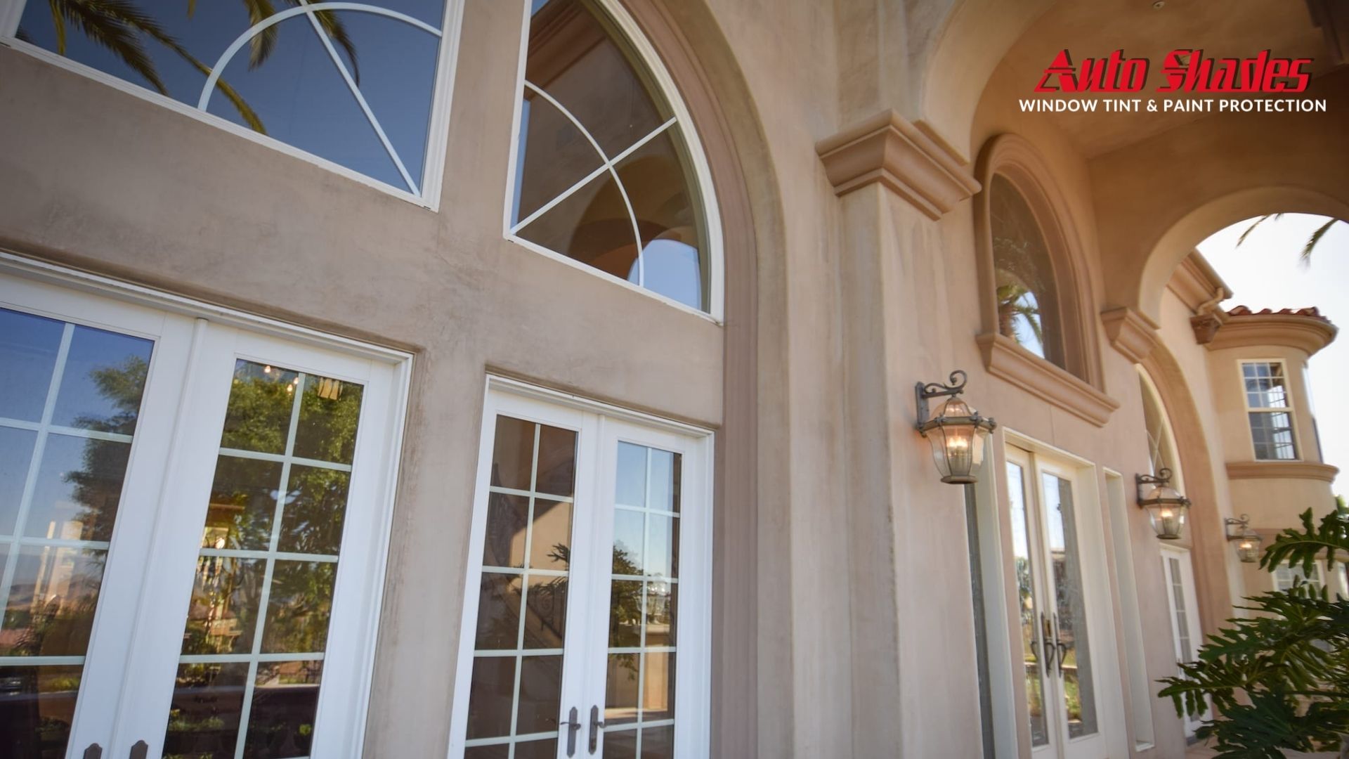 Exterior of a large upscale home with white French doors and arched windows, all featuring residential window tinting for UV protection and privacy.